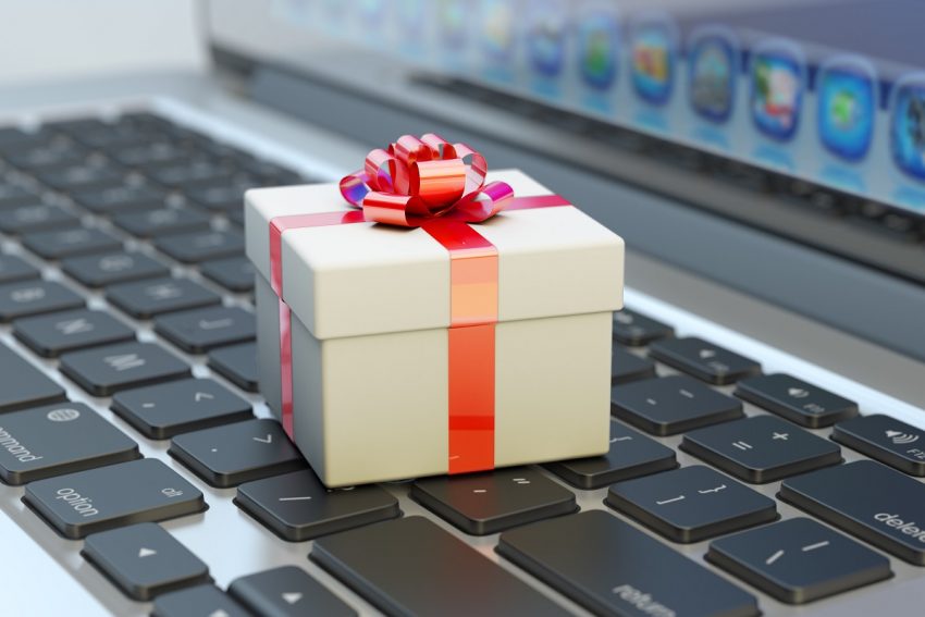 White gift box with red ribbon bow on computer laptop keyboard macro view